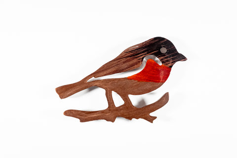 Aluminium bird figurine on a branch with a red breast on a white background
